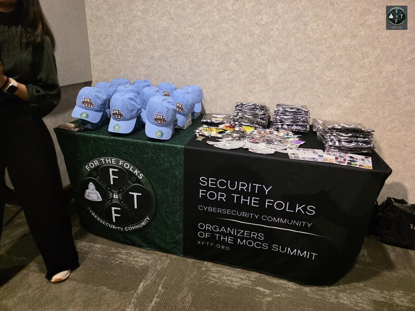 Security For the Folks community table with hats and stickers