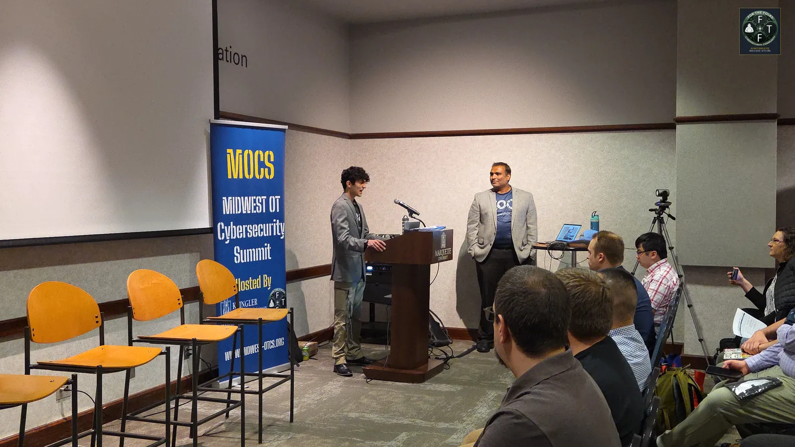 Two presenters opening the conference at the podium