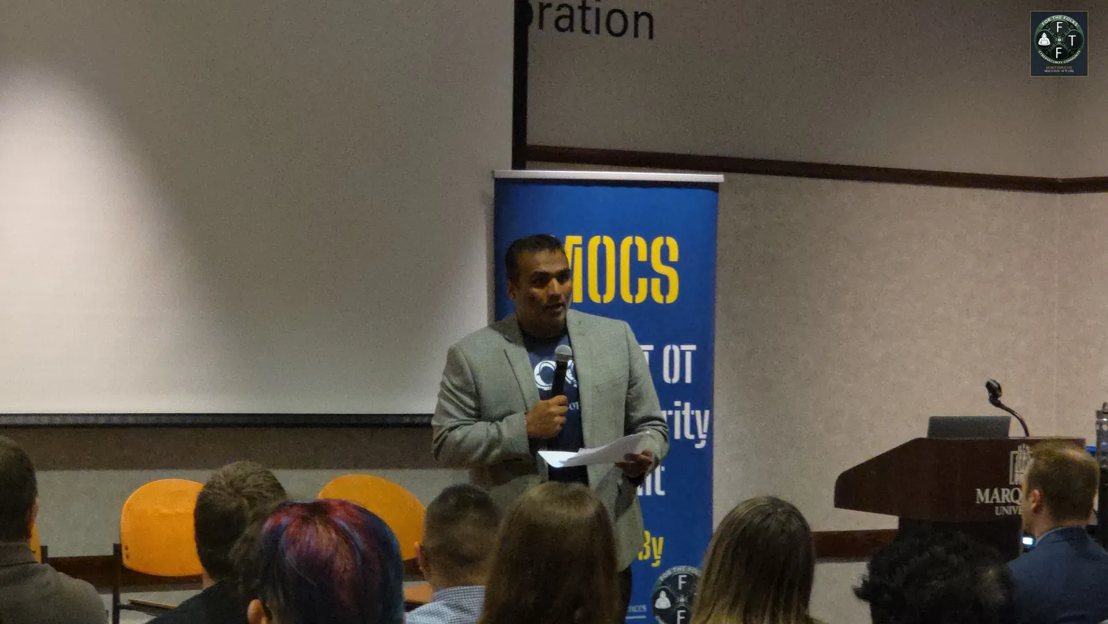 Speaker at the mic with MOCS banner